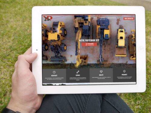 Main tenant une tablette présentant la création de site d'annonces de Vendée Distribution
