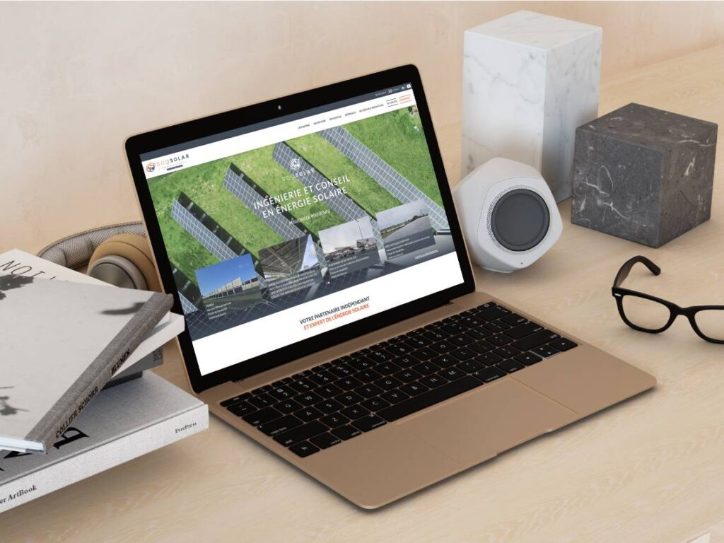 Présentation du site catalogue de SOG Solar sur un écran d'ordinateur portable posé sur un bureau avec lunettes