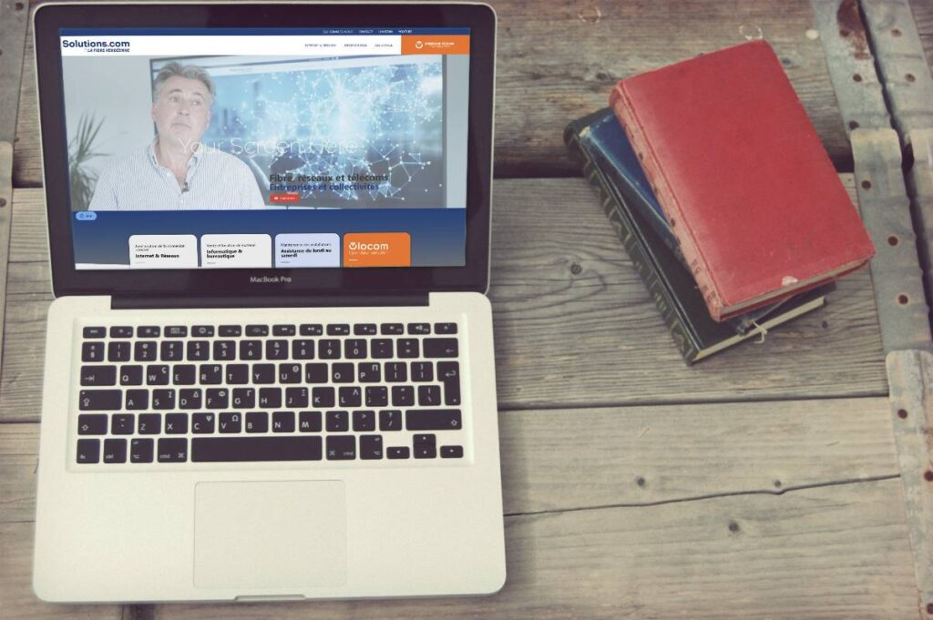Ordinateur portable à côté d'un agenda rouge présentant la création du site internet de Vendée Solutions