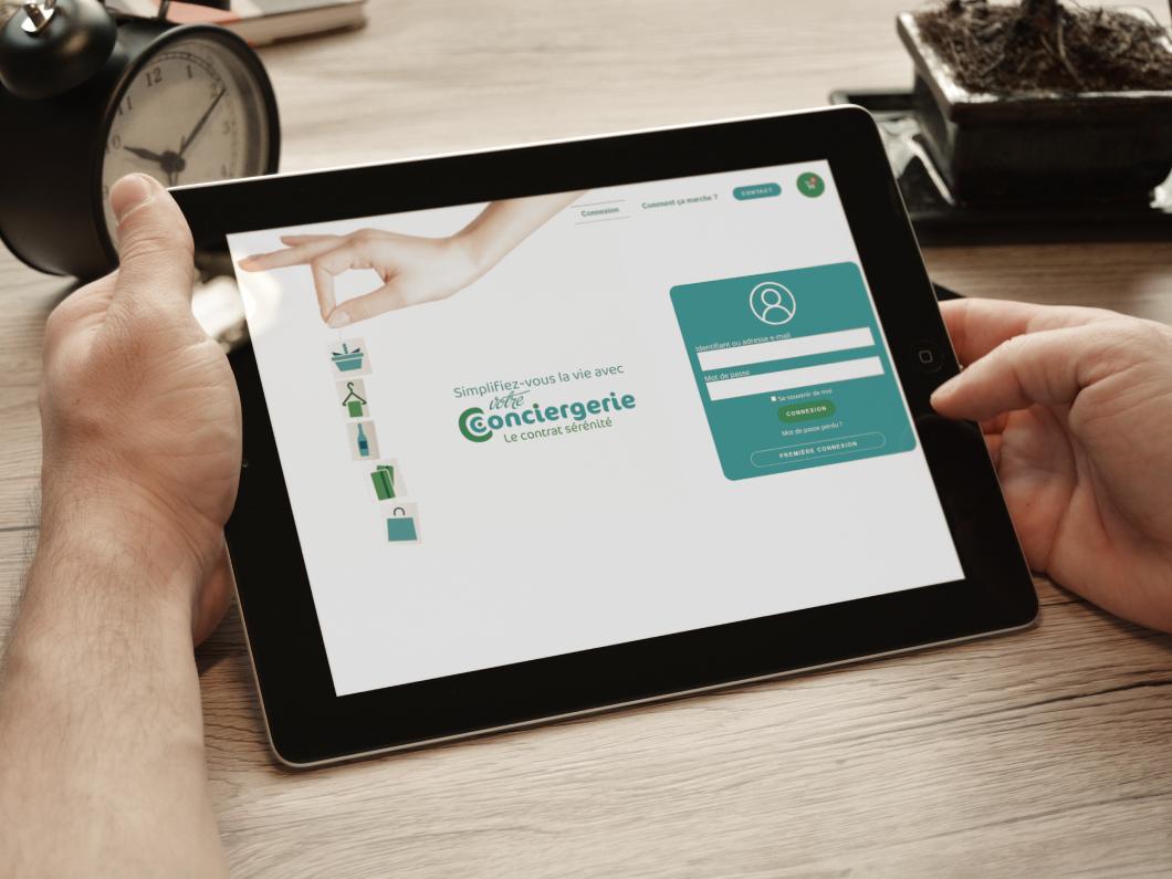 Mains d'homme tenant une tablette affichant la création de boutique en ligne de Votre conciergerie